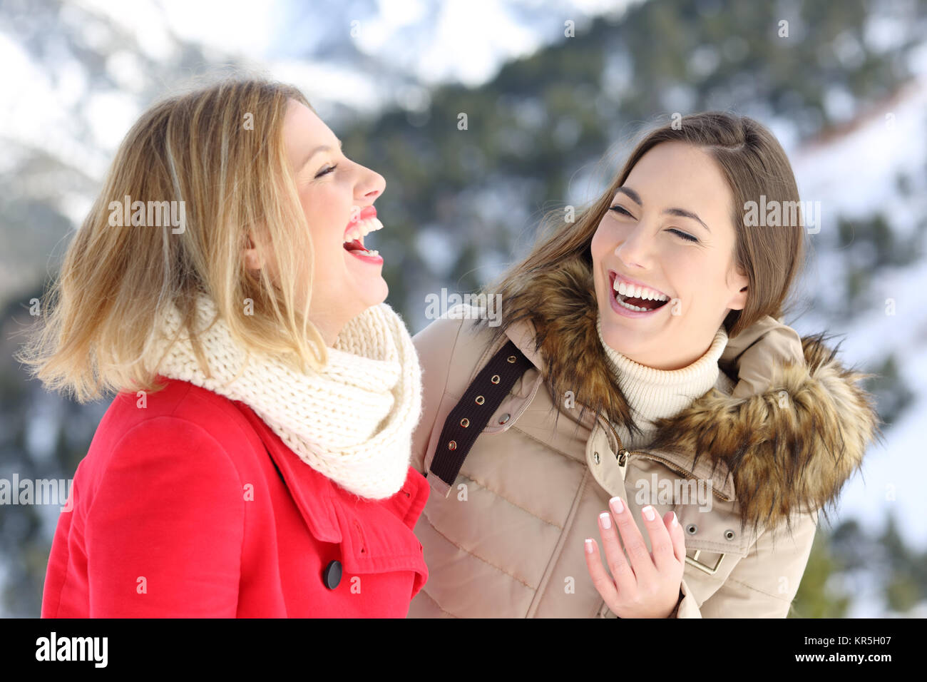 Two happy friends laughing loud enjoying winter holidays in a snowy mountain Stock Photo