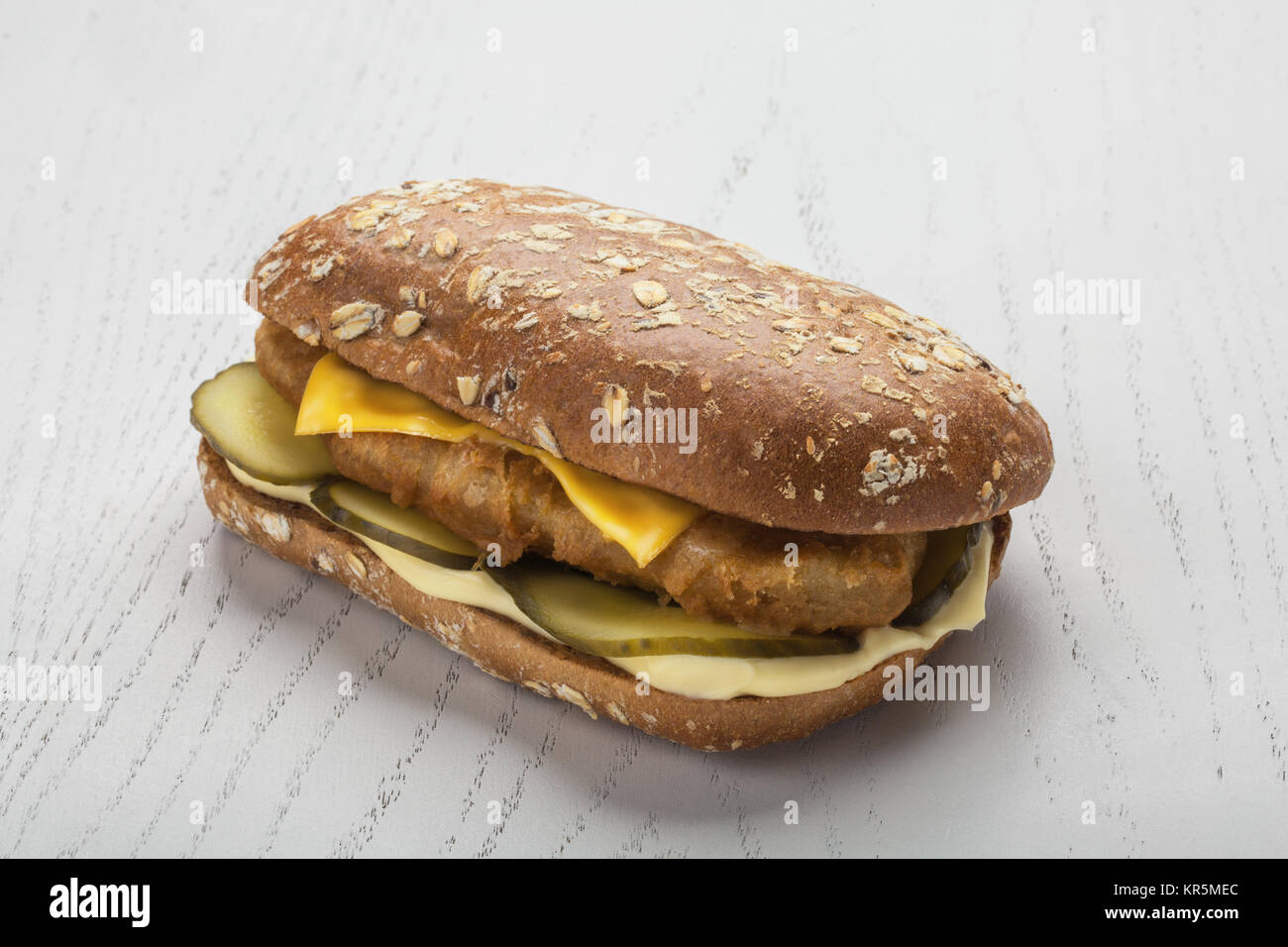 Schnitzel Burger with pickle and two kinds of cheese over white wooden