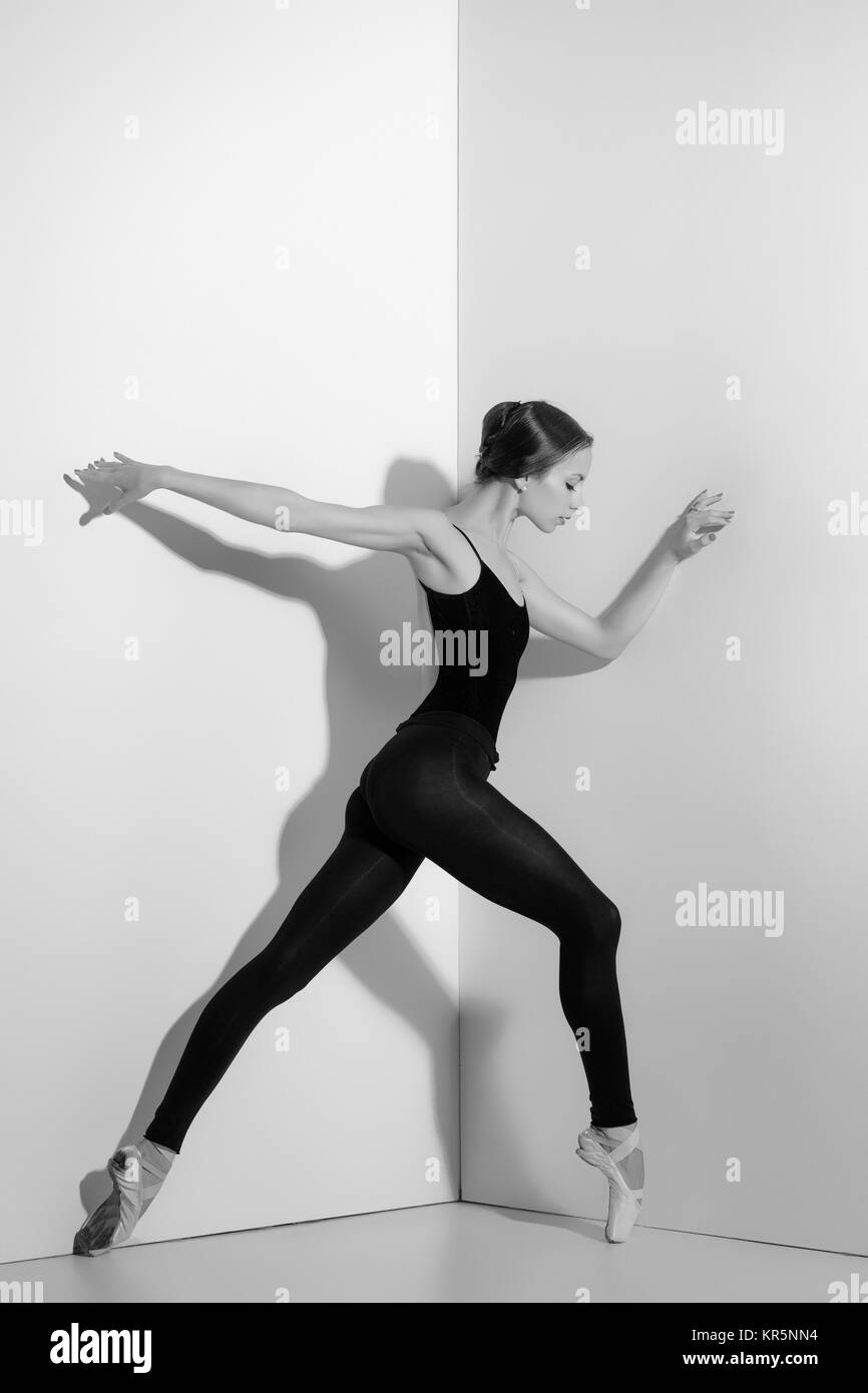 Ballerina in black outfit posing on pointe shoes, studio background. Stock Photo