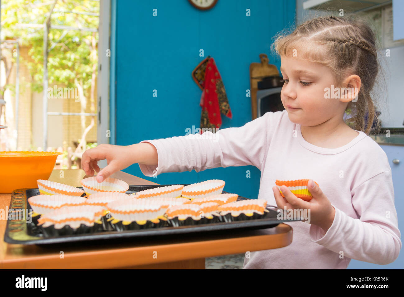 The child lays on a baking tins Easter cupcakes Stock Photo