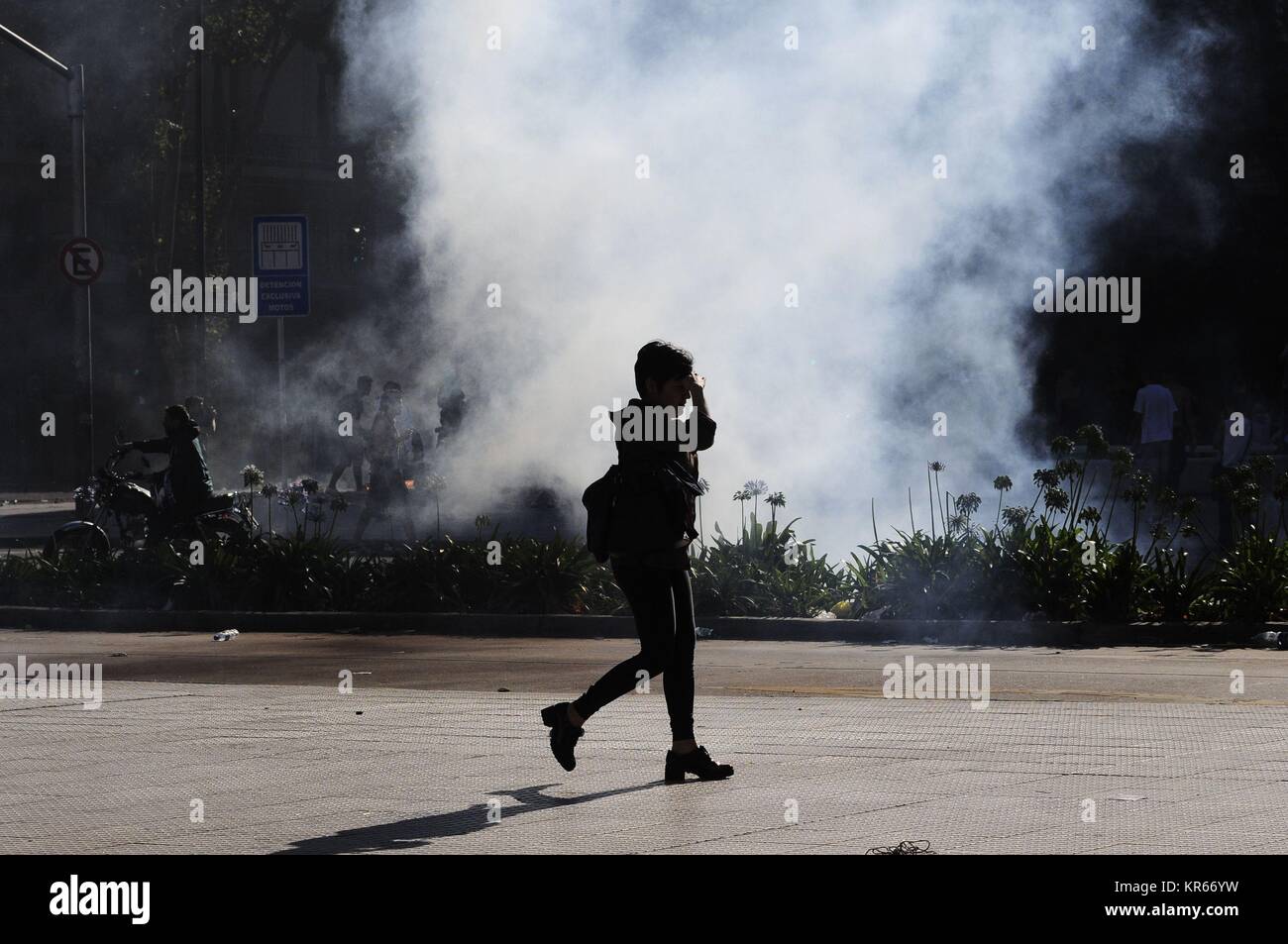 Buenos Aires, Buenos Aires, Argentina. 19th Dec, 2017. Commuting from work, a woman passes by a cloud of tear gas during violent protests against reforms to pension laws promoted by President Mauricio Macri. Credit: Patricio Murphy/ZUMA Wire/Alamy Live News Stock Photo