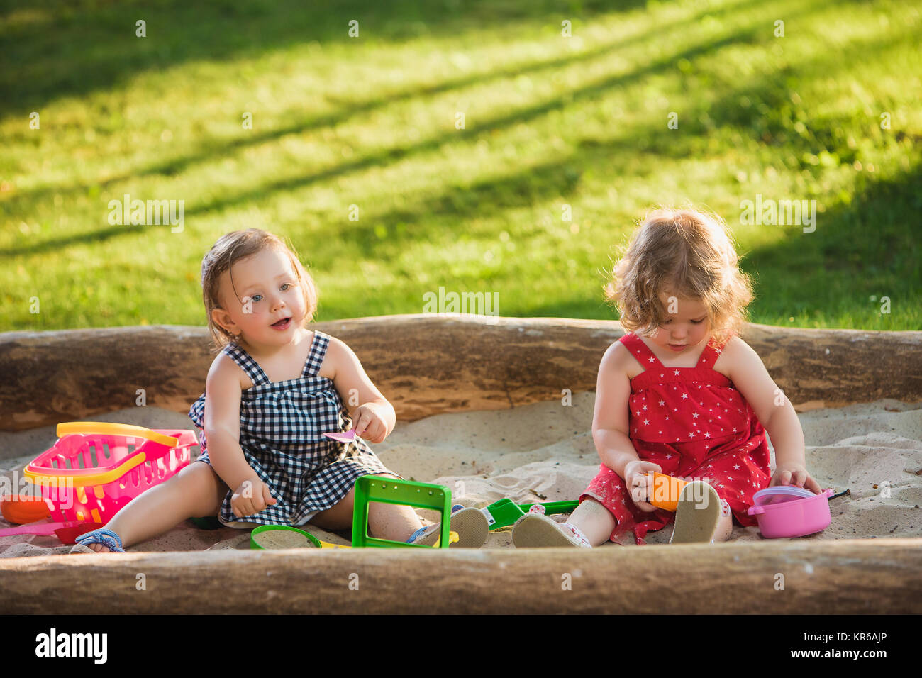 The two little baby girls playing toys in sand Stock Photo - Alamy