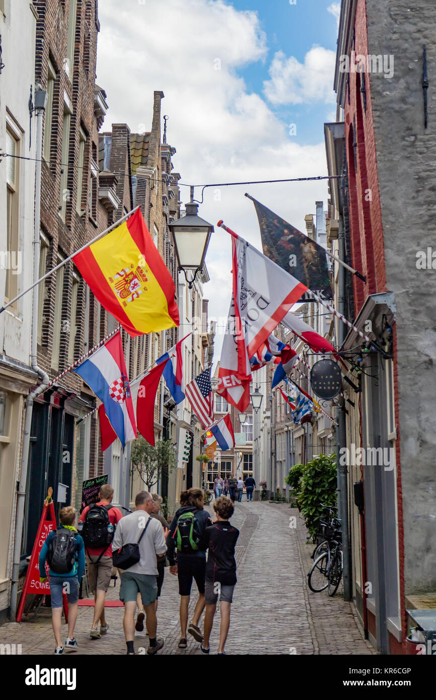 Tourists walking down a narrow flag lined street at Dordrecht, South Holland, Netherlands. Stock Photo