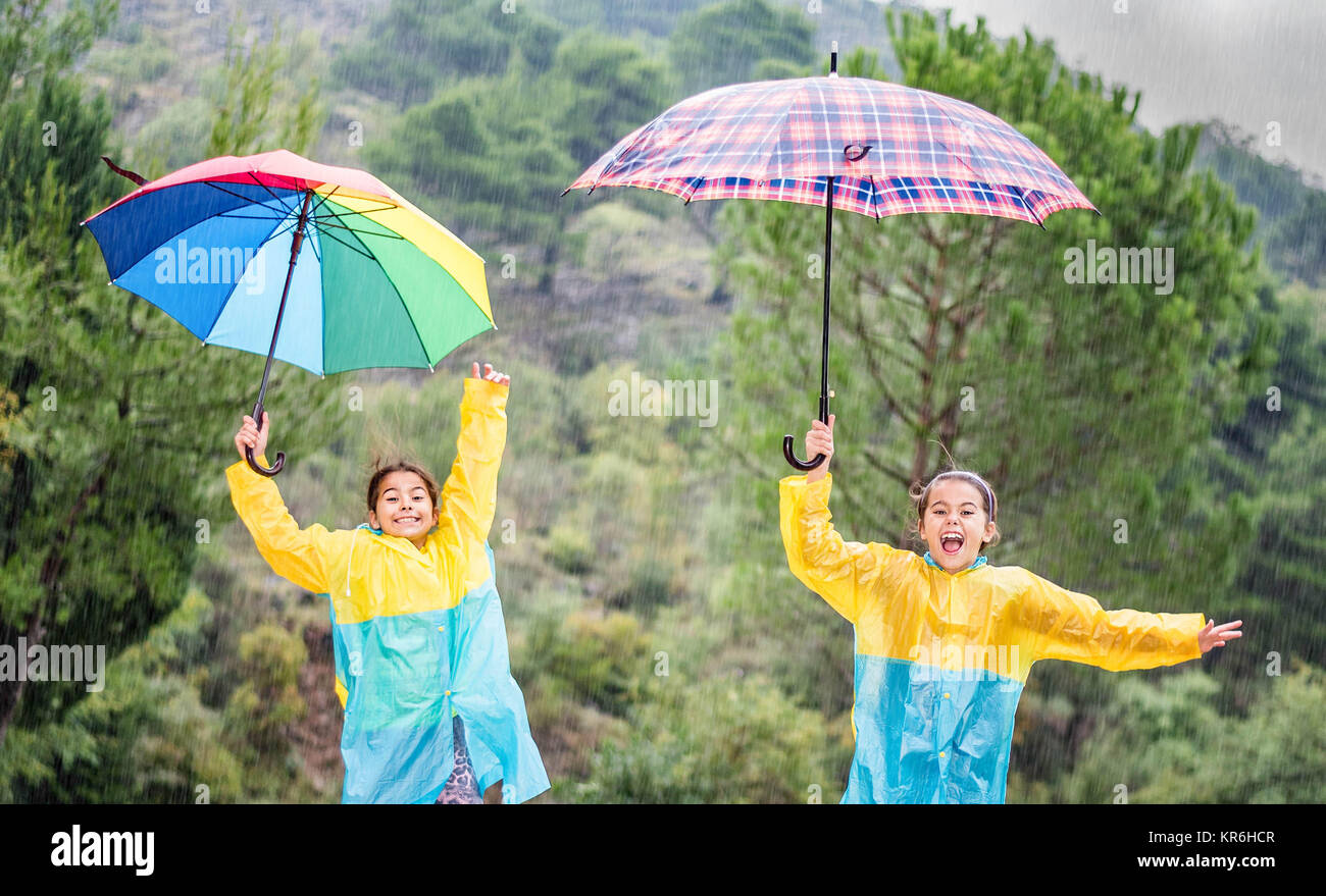 Children with colorful rainbow umbrella,raincoats and waterproof boots