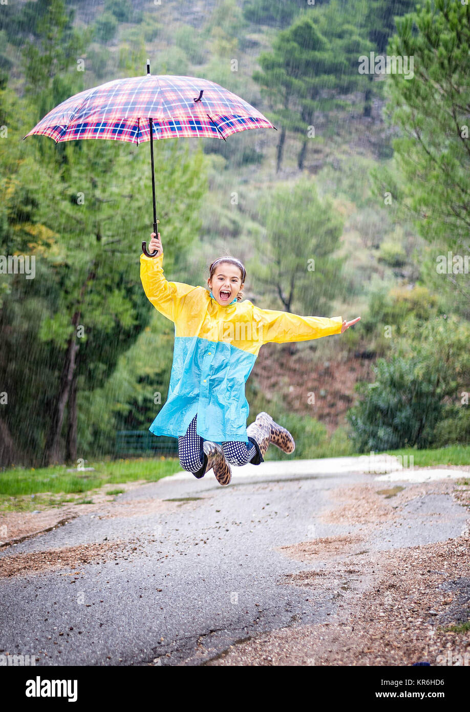 Little girl with colorful umbrella,raincoat and waterproof boots play