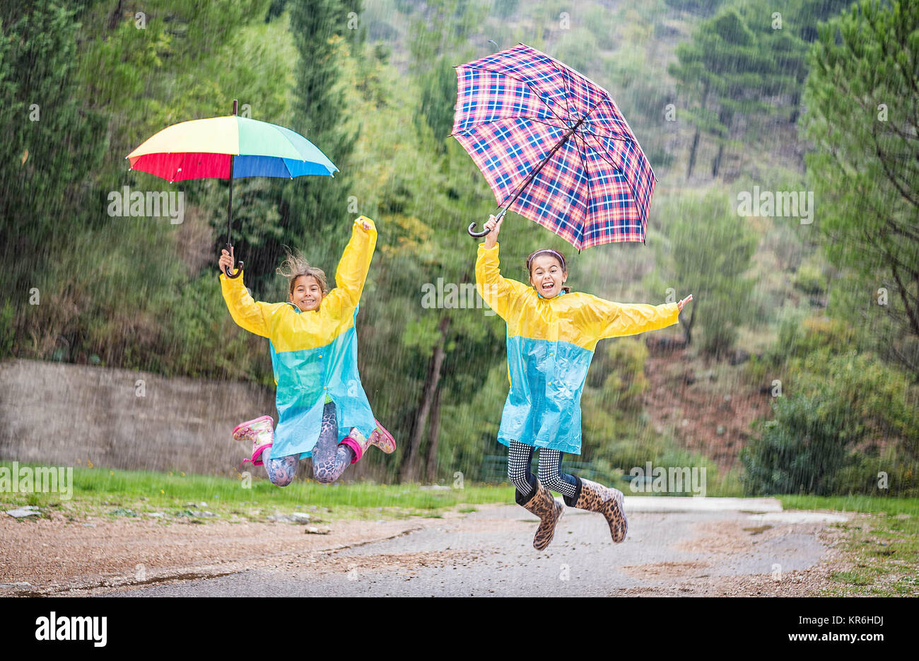 Children with colorful rainbow umbrella,raincoats and waterproof boots