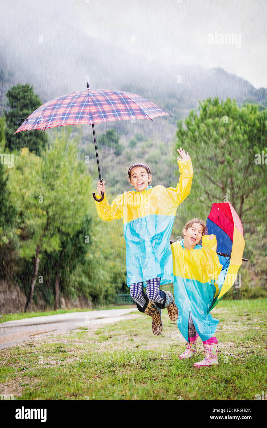 Children with colorful rainbow umbrella,raincoats and waterproof boots