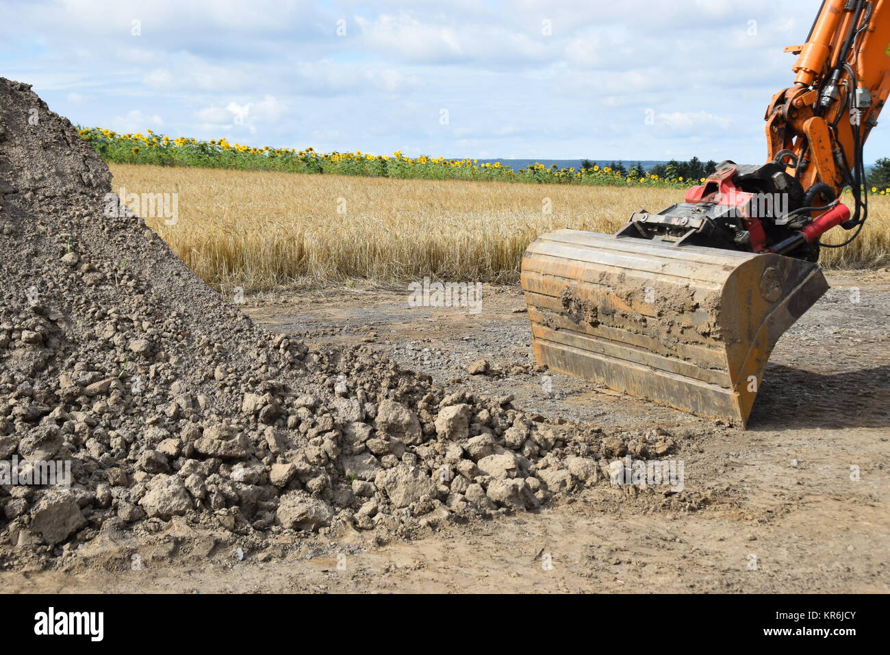 wheel excavator with bucket grave in front of a wheat field Stock Photo