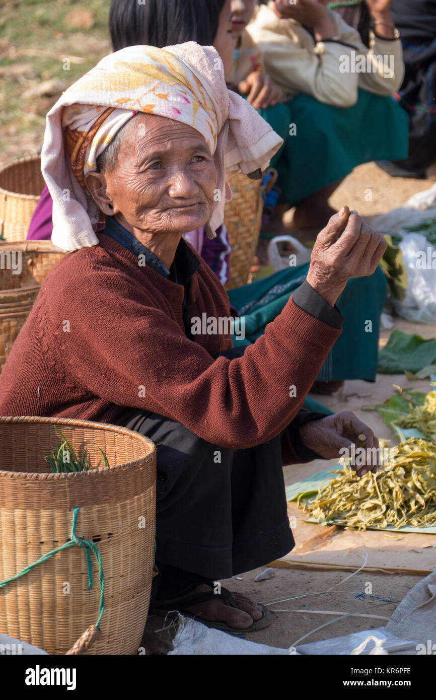 Burmese woman seller, Inthein market, Burma , March 2012: A senior Burmese woman wearing an ethnic headscarf sells local vegetables at Inthein market Stock Photo