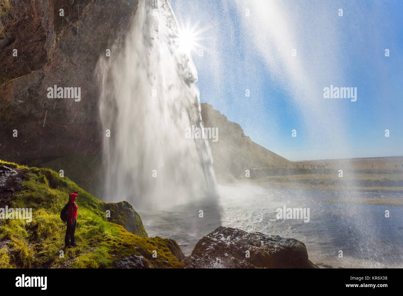person standing on the edge of rock near a waterfall cascade over a ...