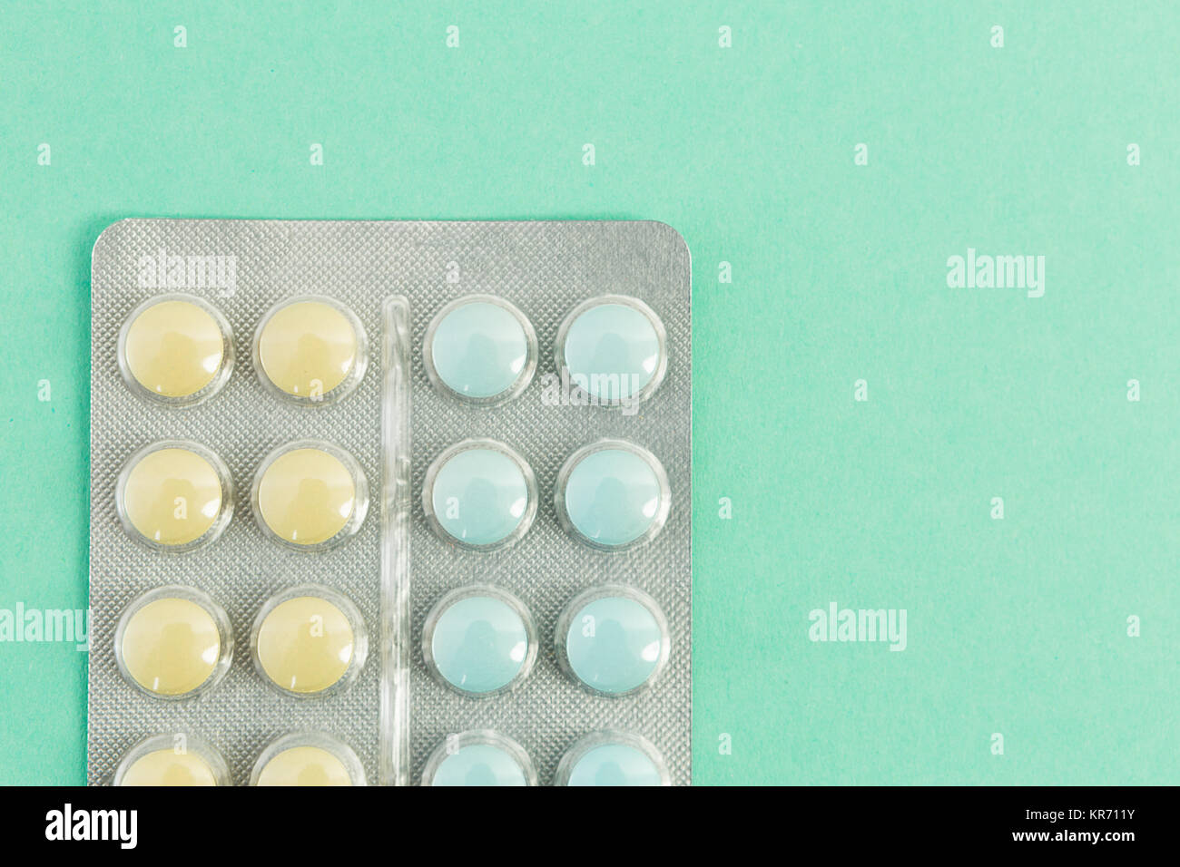 Blue and yellow pill blisters on green background with copy text space