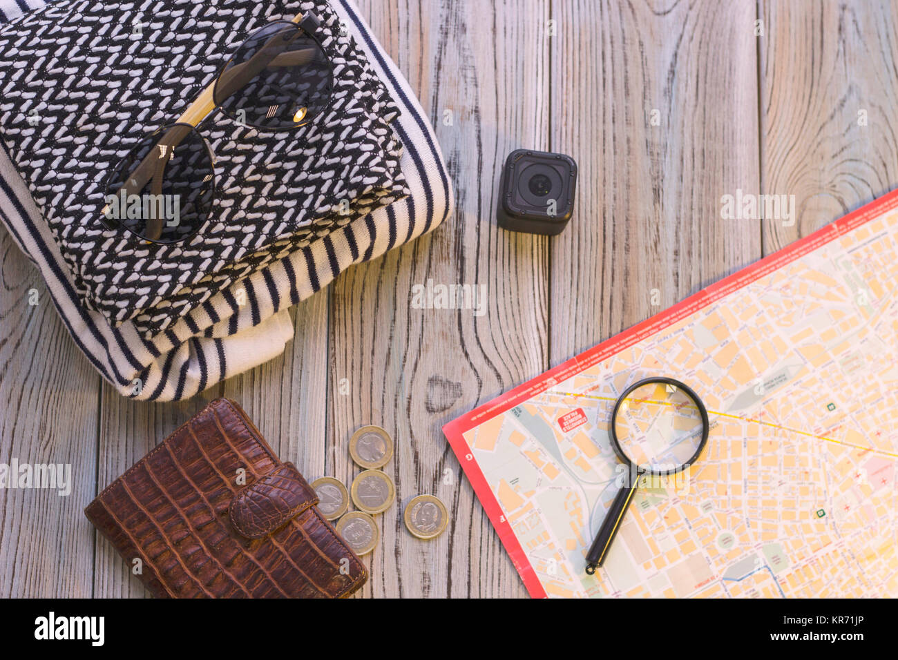 Prepare for vacation with tourist's items- patterned clothes, sunglasses, an action camera, a map, magnifying glass and a leather wallet with coins on Stock Photo