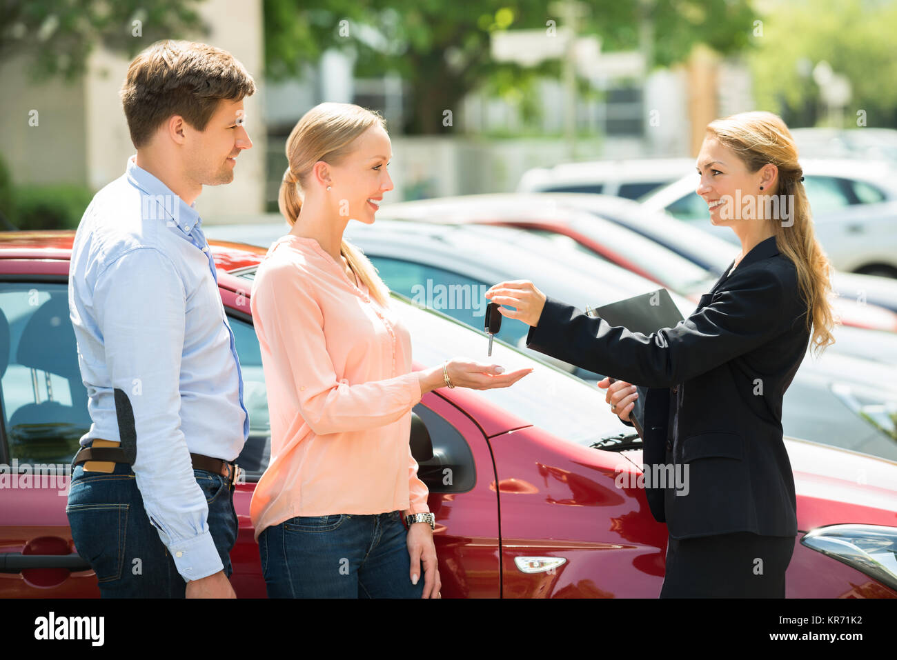 Dealer Giving Car Key To Couple Stock Photo - Alamy