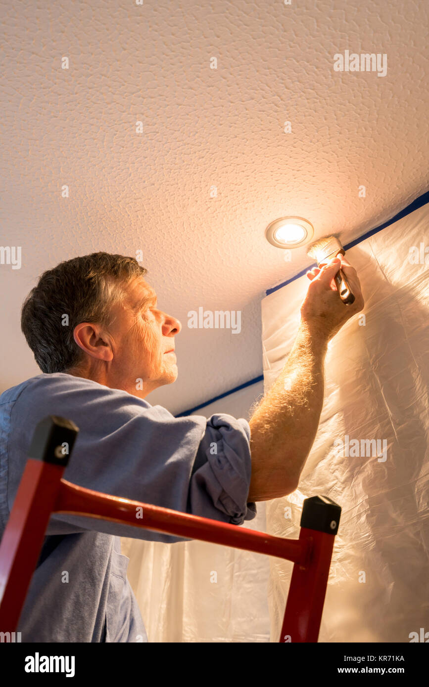 Senior adult man painting ceiling of kitchen Stock Photo