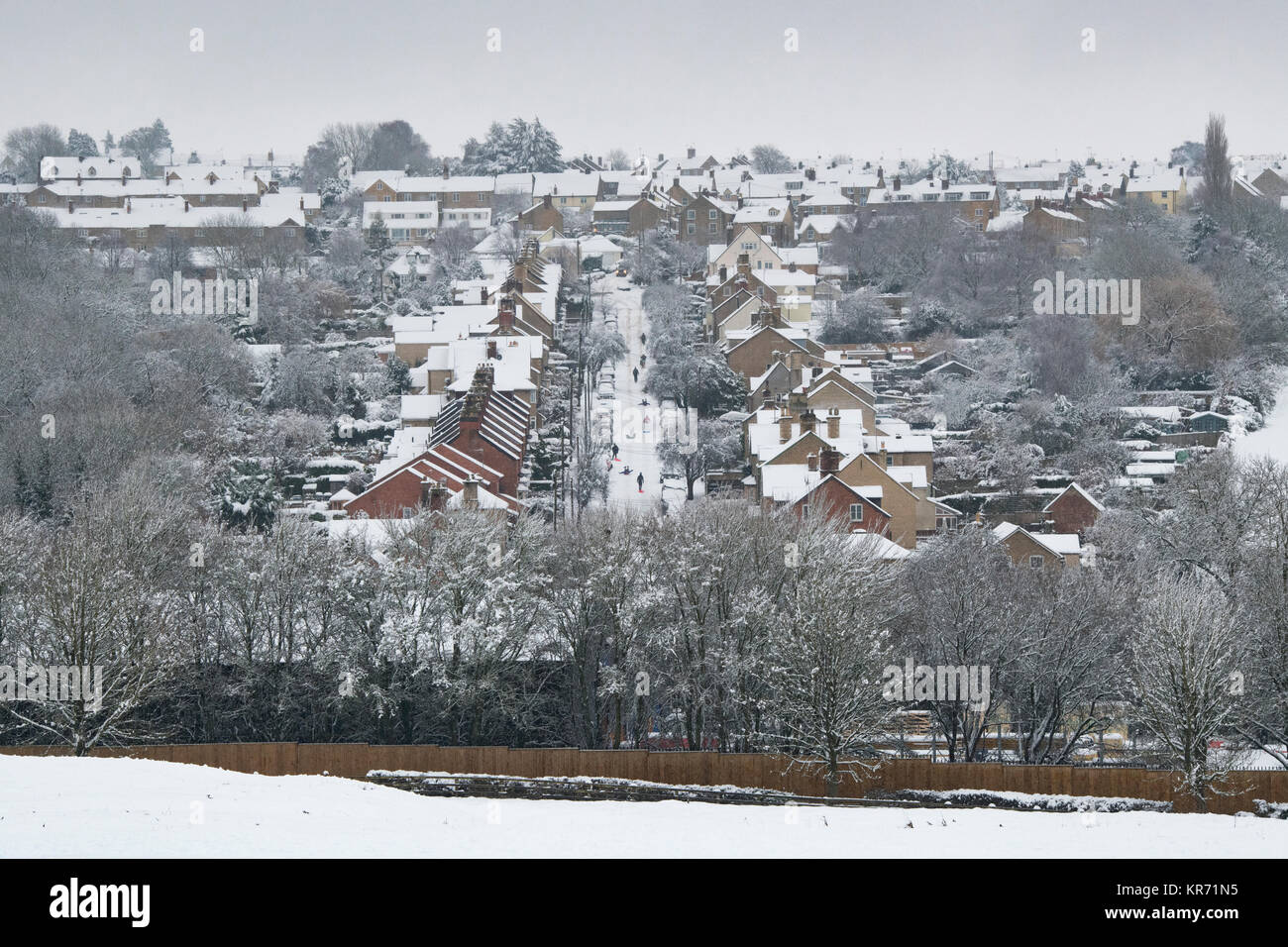 Looking over Chipping Norton in the snow in December. with people sledging down a steep road. Chipping Norton, Cotswolds, Oxfordshire, England Stock Photo