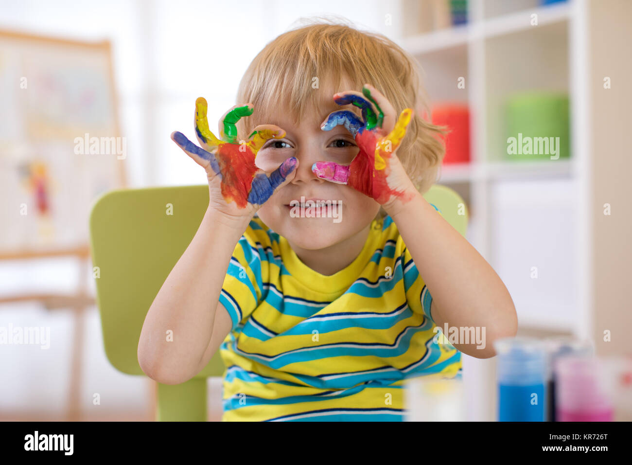 cute cheerful kid with hands painted in bright colors Stock Photo