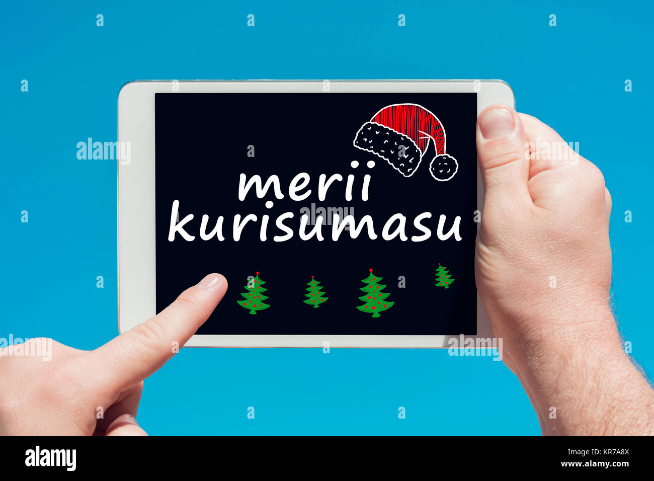 Man Holding A Tablet Device With Text In Japanese Merii Kurisumasu Merry Christmas And Touching The Screen With A Finger With Blue Sky In Backgrou Stock Photo Alamy