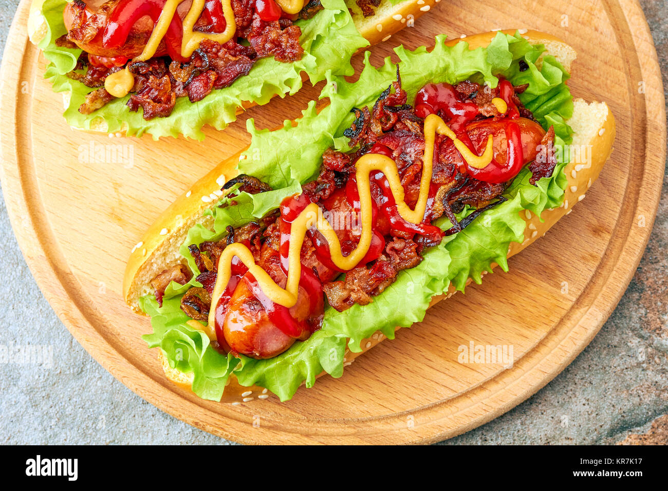 Two homemade hot dogs with lettuce, bacon and onion toppings Stock