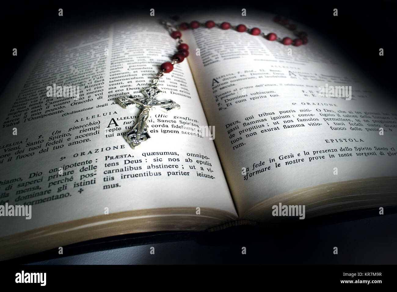 Holy Bible open with a red rosary on top Stock Photo