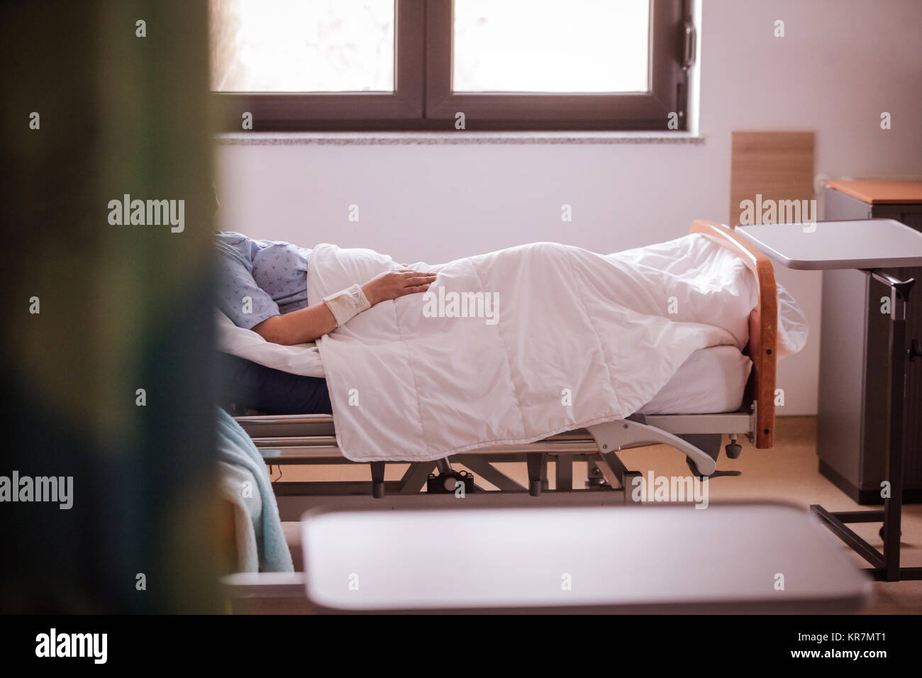 Terminally ill patient sits in bed at a hospice Stock Photo