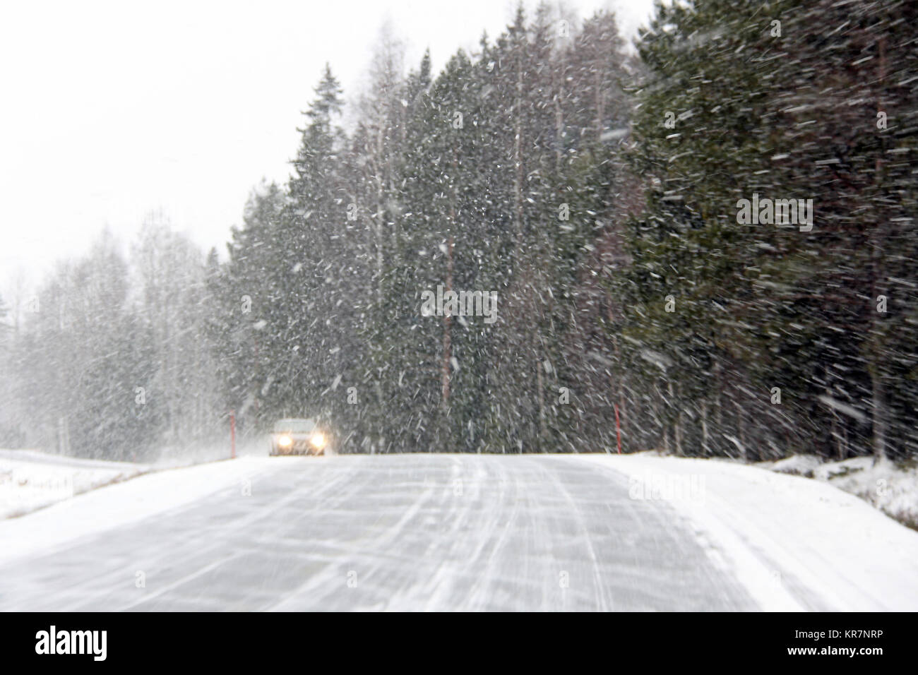 Car driving along a rural road during a blizzard. Stock Photo