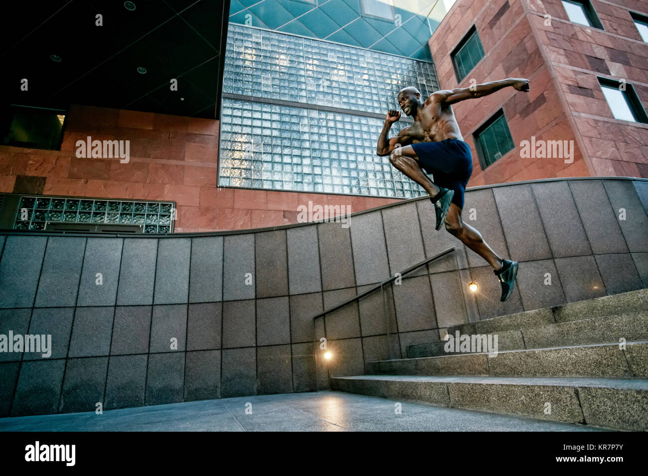 Black man running and jumping on stairs in city Stock Photo