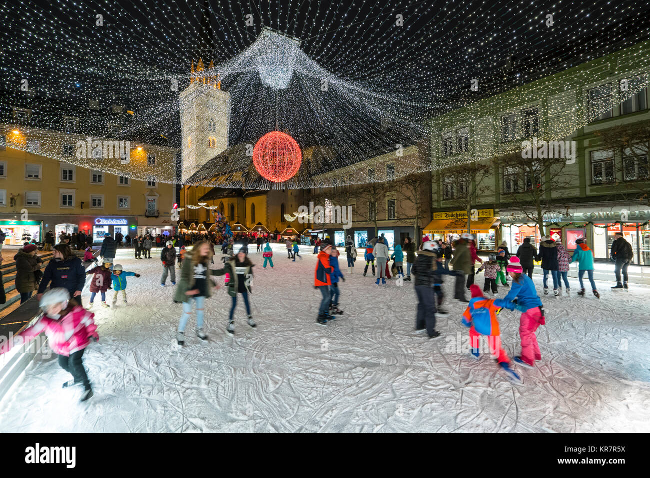 people are skating in the ice rink in a square in the historic center of Villach, Austria Stock Photo