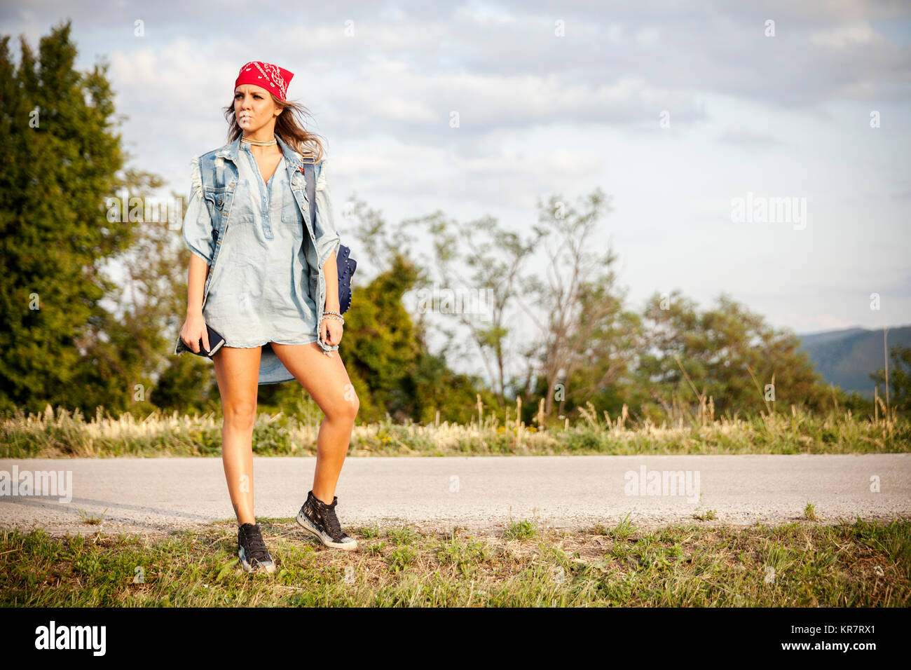 young woman hitchhiking on a country road Stock Photo