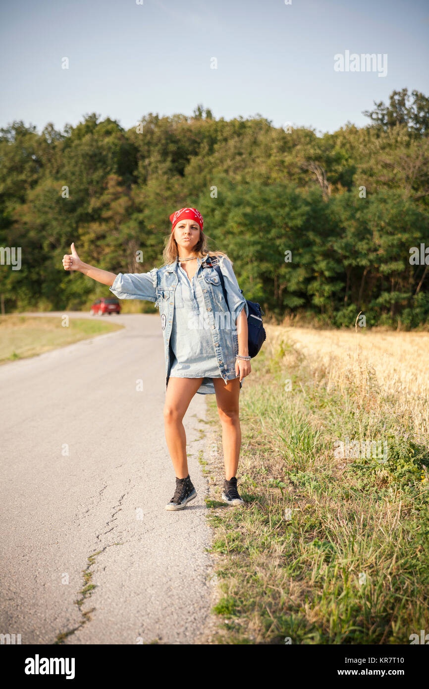 young woman hitchhiking on a country road Stock Photo Alamy