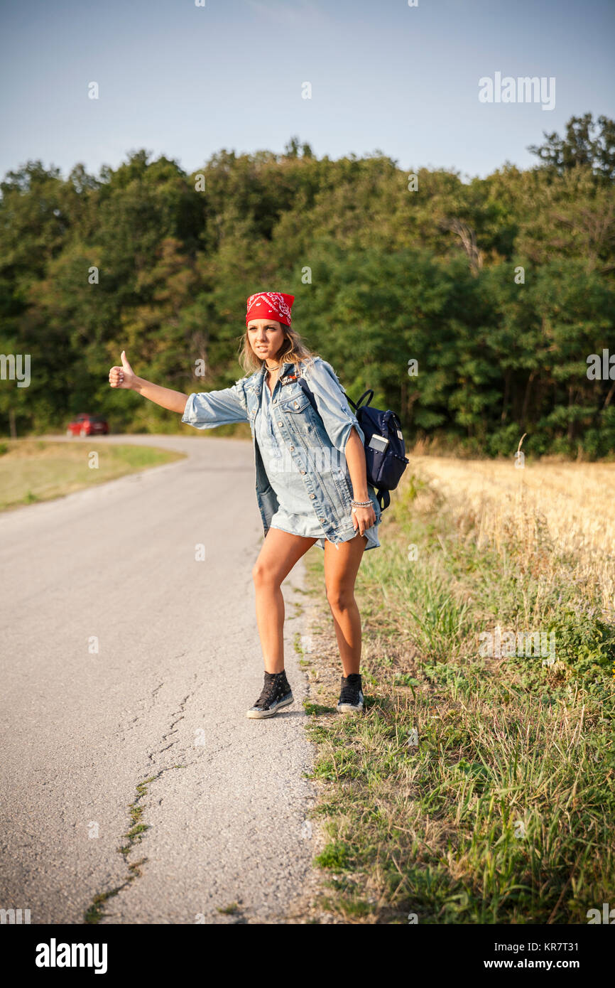 young woman hitchhiking on a country road Stock Photo