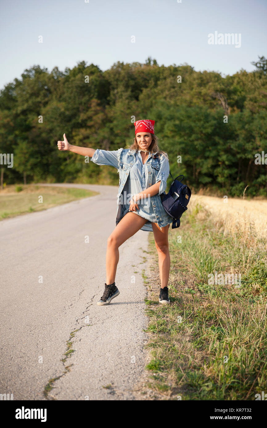 young woman hitchhiking on a country road Stock Photo