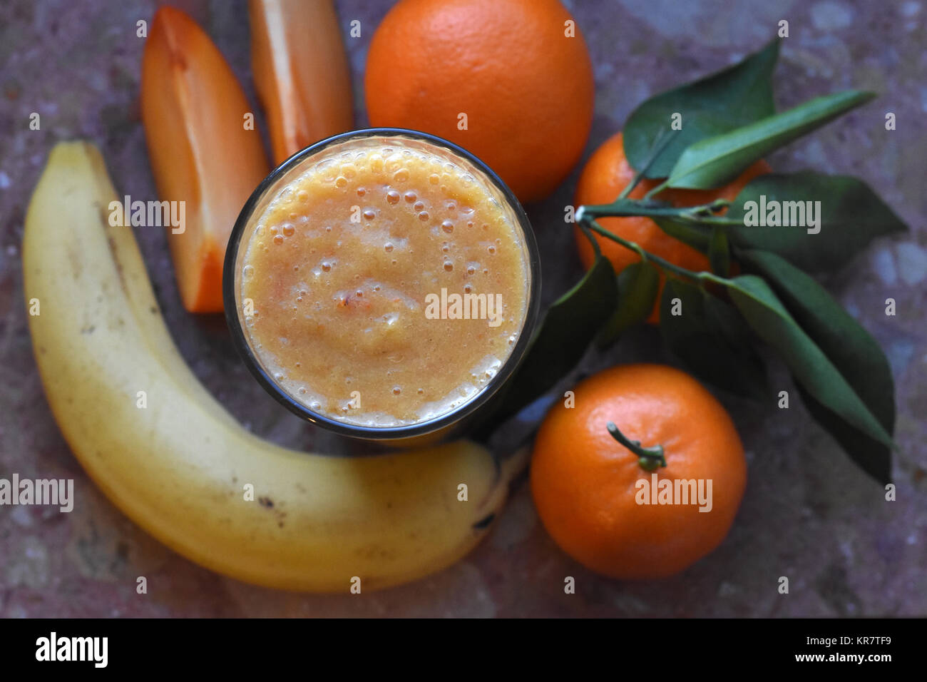 still life of smoothie glass with persimmon, banana, mandarins on the