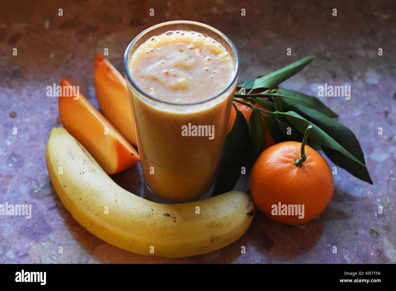 still life of smoothie glass with persimmon, banana, mandarins on the