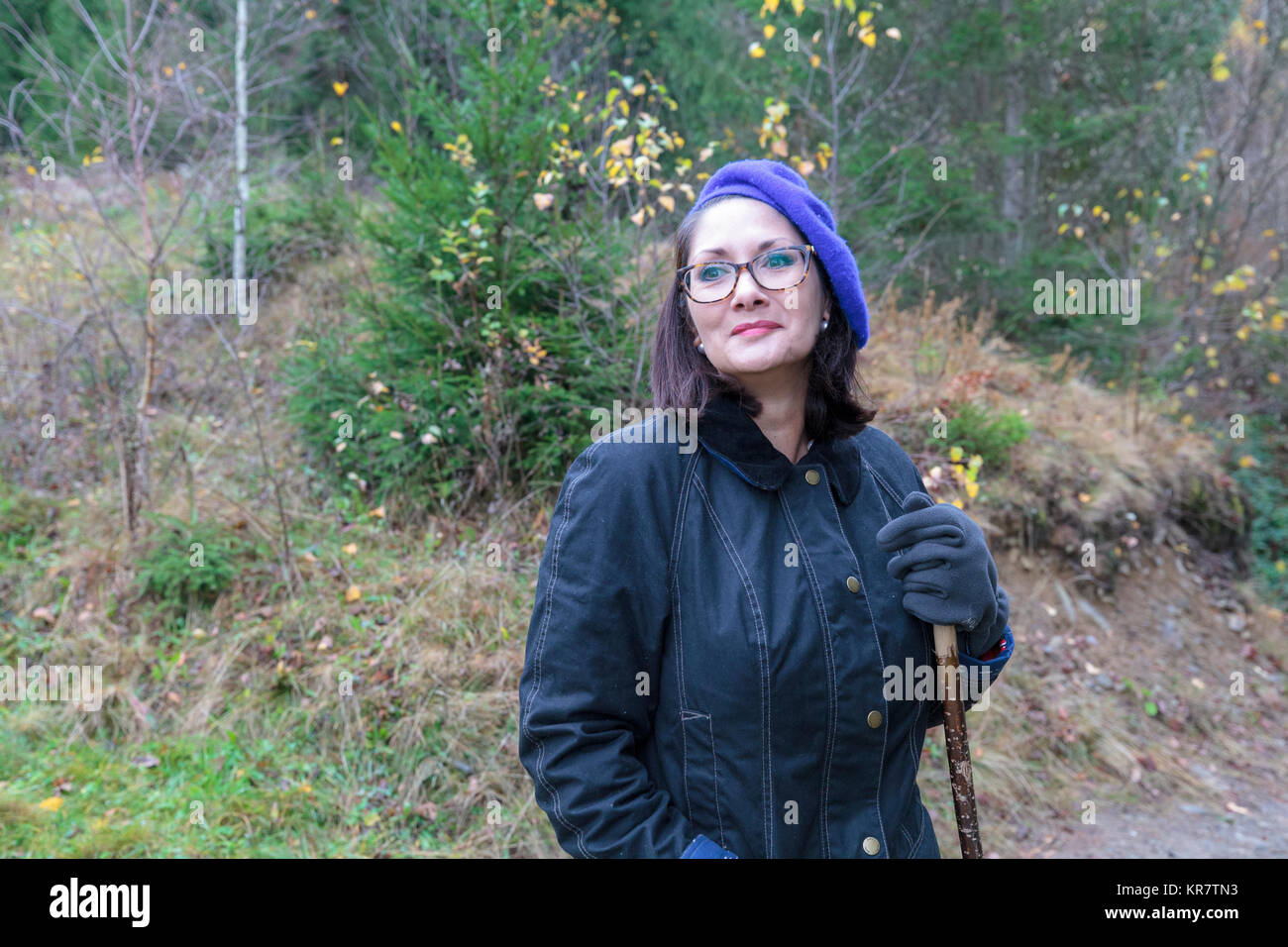 Lady with glasses wearing blue beret standing in the woods Stock Photo