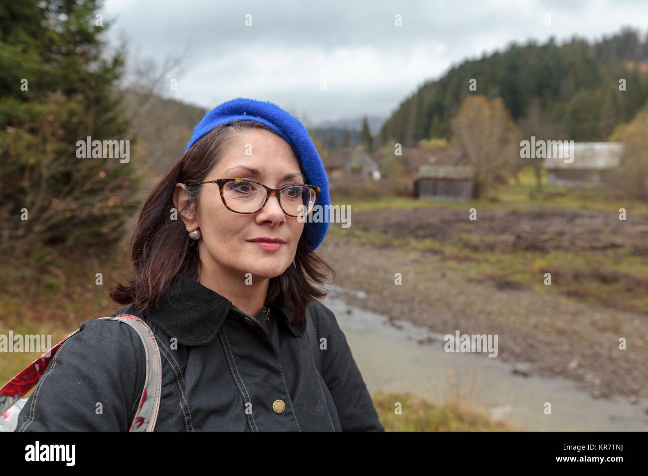 Lady with glasses wearing blue beret standing in the woods Stock Photo