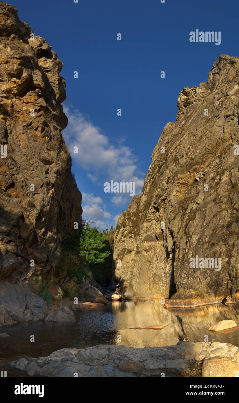 High cliffs seen from below and forming a gorge at Fragas de Sao Simao. Small natural water dam of water eroded rocks blocking River Alge. Figueiro do Stock Photo