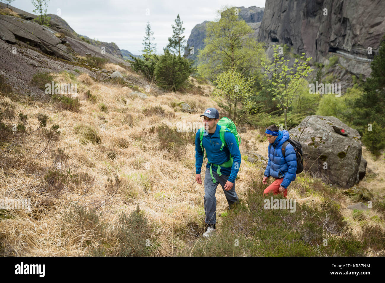 Rock climbers walk through a wood to a climbing route Stock Photo
