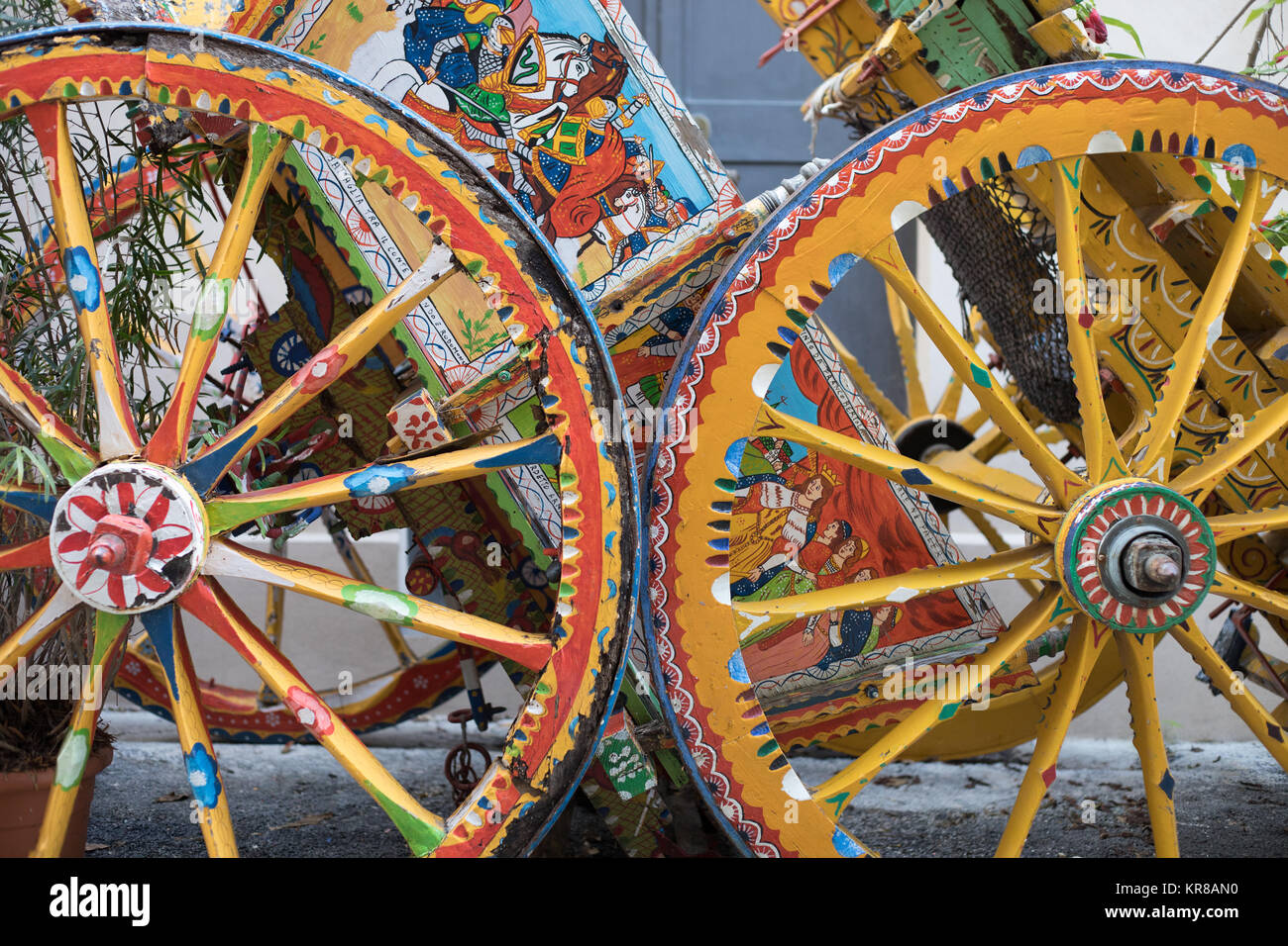 Weels of wood cart, painted with multi colored scenes of typical farmer life and allegoric scenes, as a very typical object fron Sicilian traditions. Stock Photo
