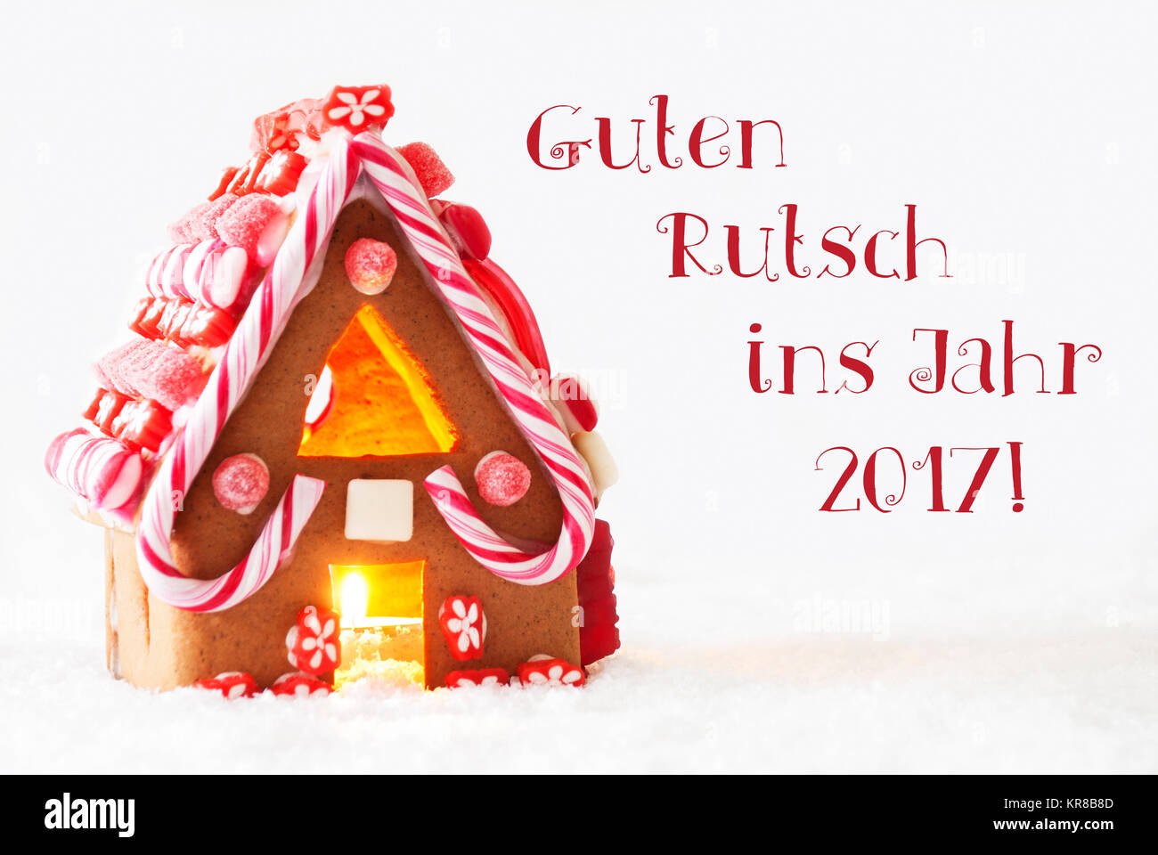 Gingerbread House In Snowy Scenery As Christmas Decoration With White Background. Candlelight For Romantic Atmosphere. German Text Guten Rutsch Ins Jahr 2017 Means Happy New Year Stock Photo
