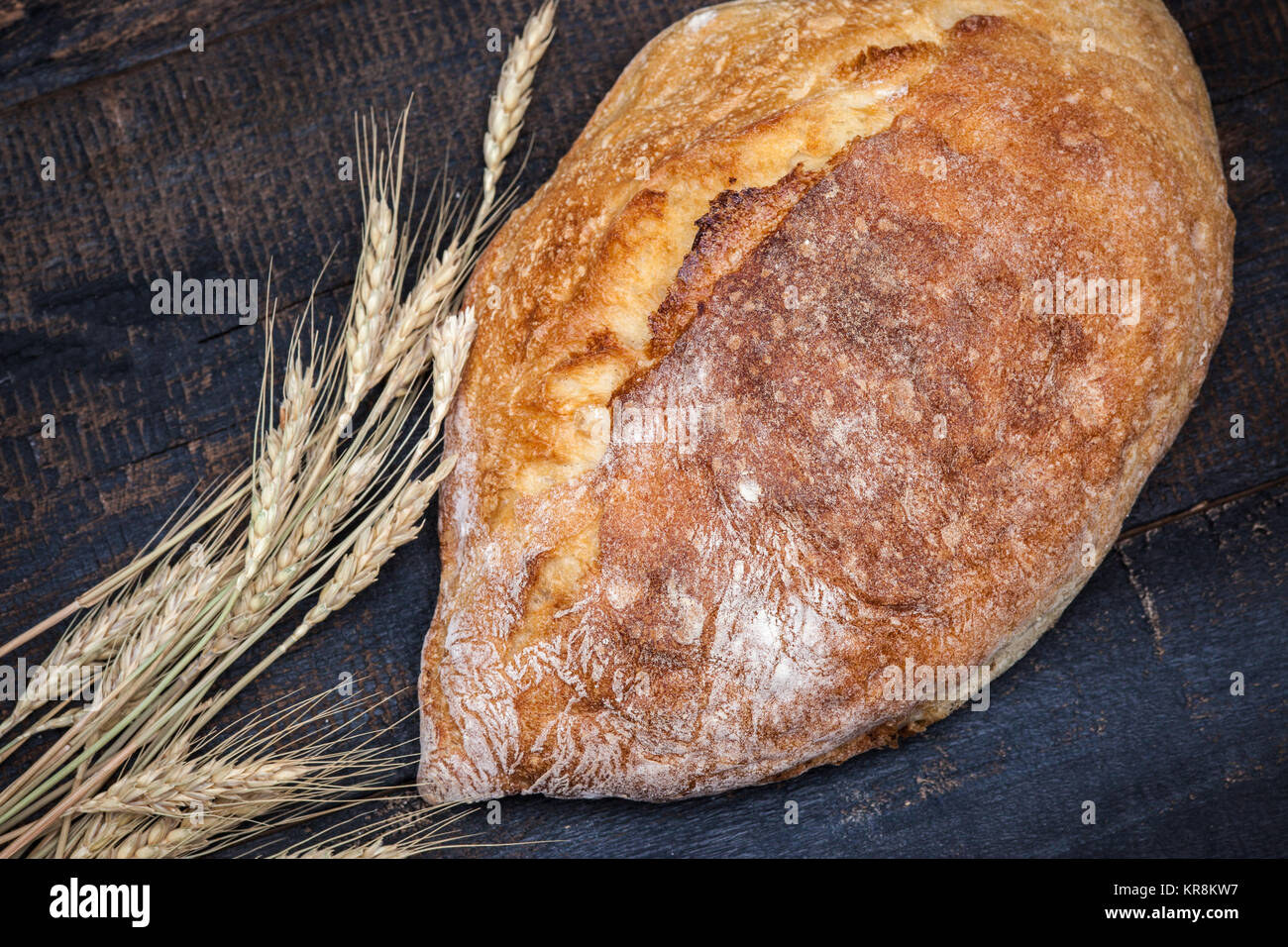 Rustic bread on wood table. Dark moody background with free text space. Stock Photo