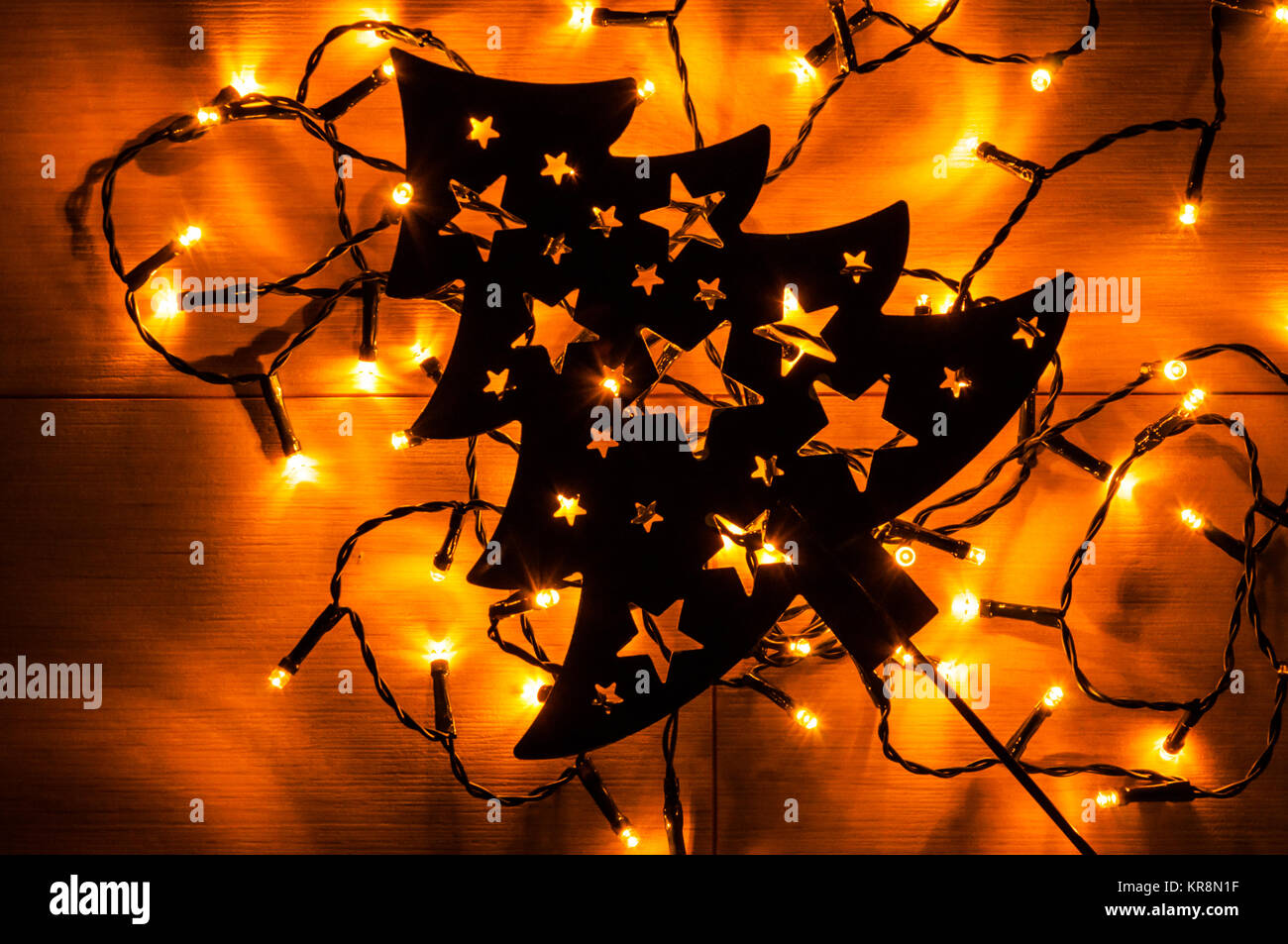 Small yellow Christmas lights behind black metal Christmas tree on the