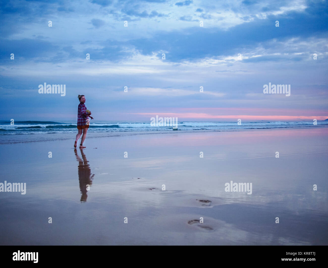 Australia, New South Wales, Woman standing on beach at dusk Stock Photo