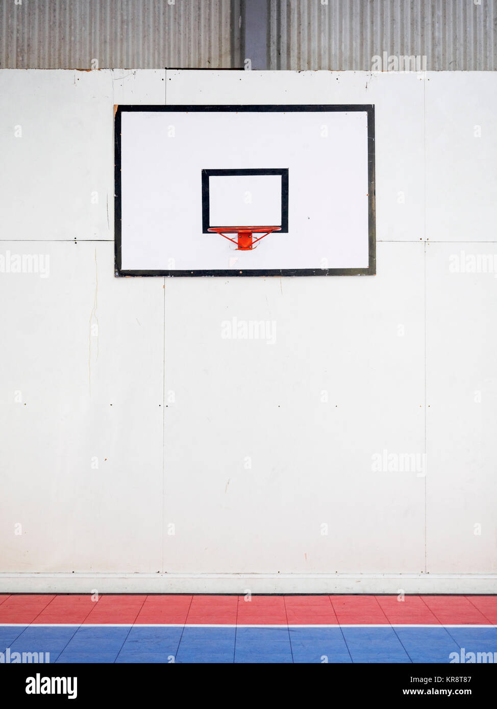 Empty basketball court with basketball hoop hanging on wall Stock Photo