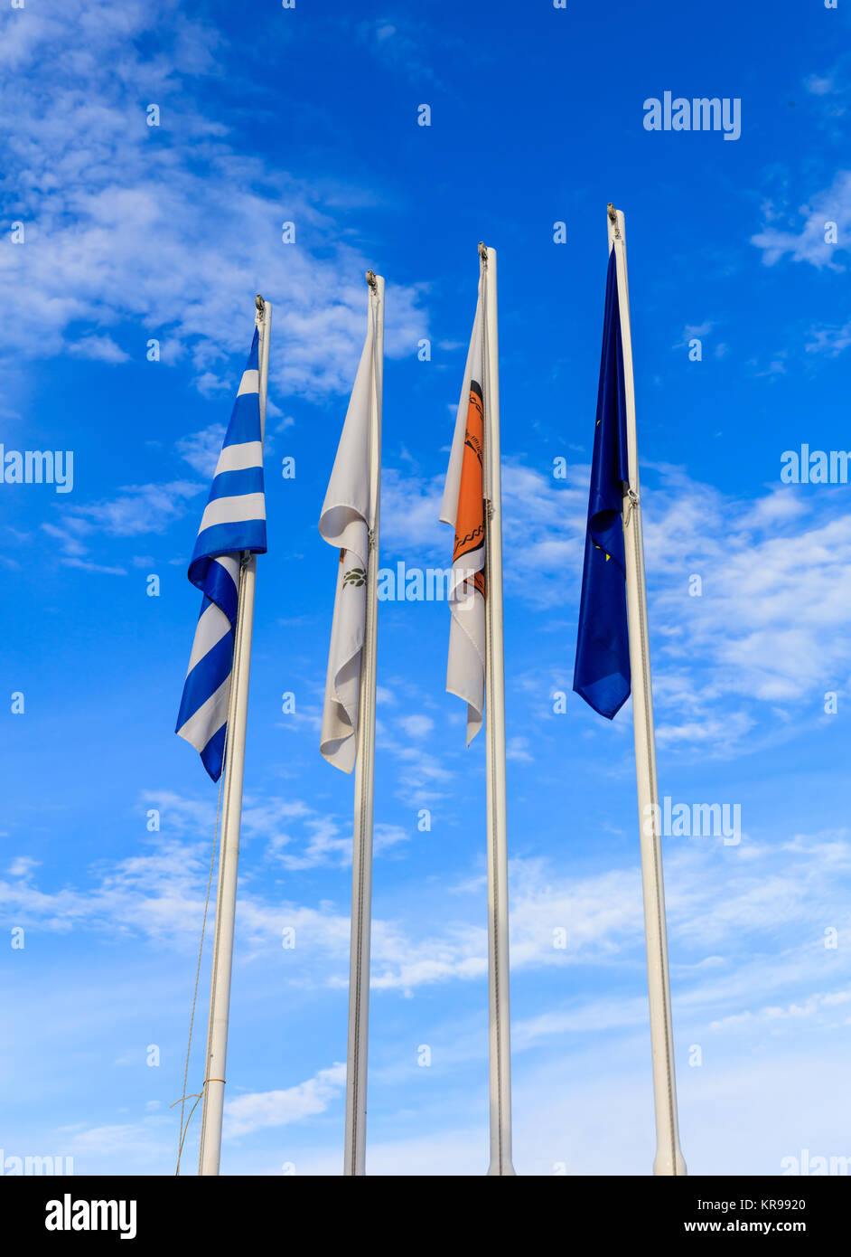 Cyprus, Greece, EU and Larnaka municipality flags on flagpoles. Cloudy sky background. Stock Photo
