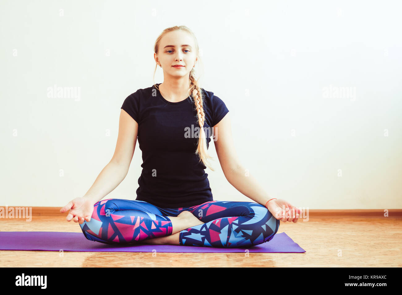young blonde woman sitting in Lotus position in the yoga room Stock ...