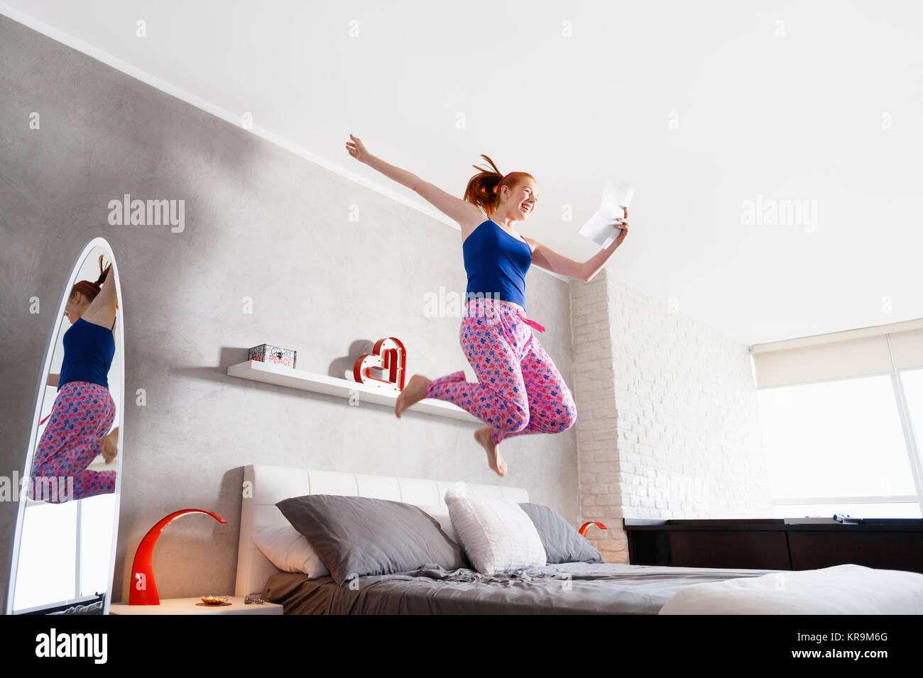 Good News For Happy Young Woman Girl Jumping On Bed Stock Photo