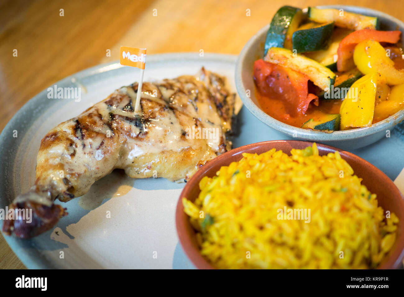 Peri-peri quarter chicken with sides of spiced rice and peri-peri vegetables from Nando's, a casual dining chain that originates from South Africa. Stock Photo