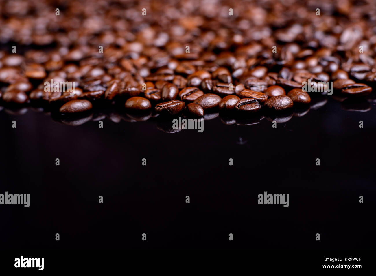 a lot of brown roasted coffee beans on black ground Stock Photo - Alamy