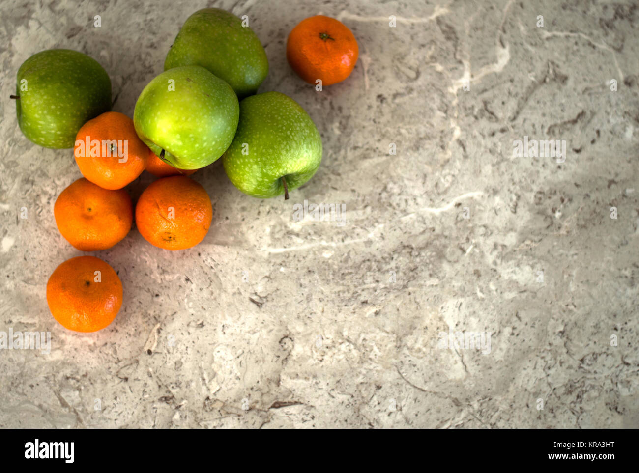 Tangerines and granny smith apples on a marble background Stock Photo