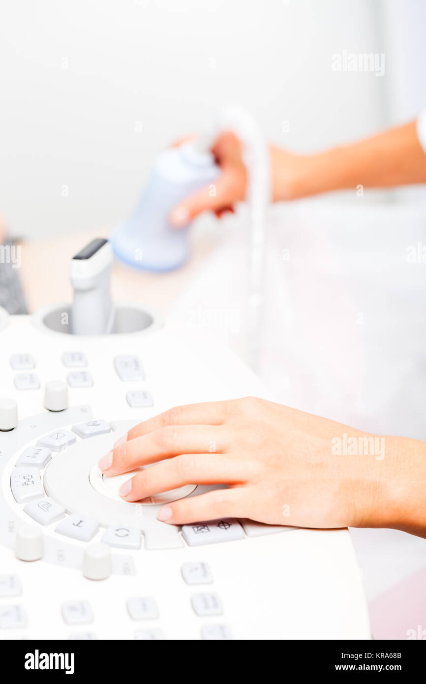 Sonographer operating ultrasound machine with trackball while scanning